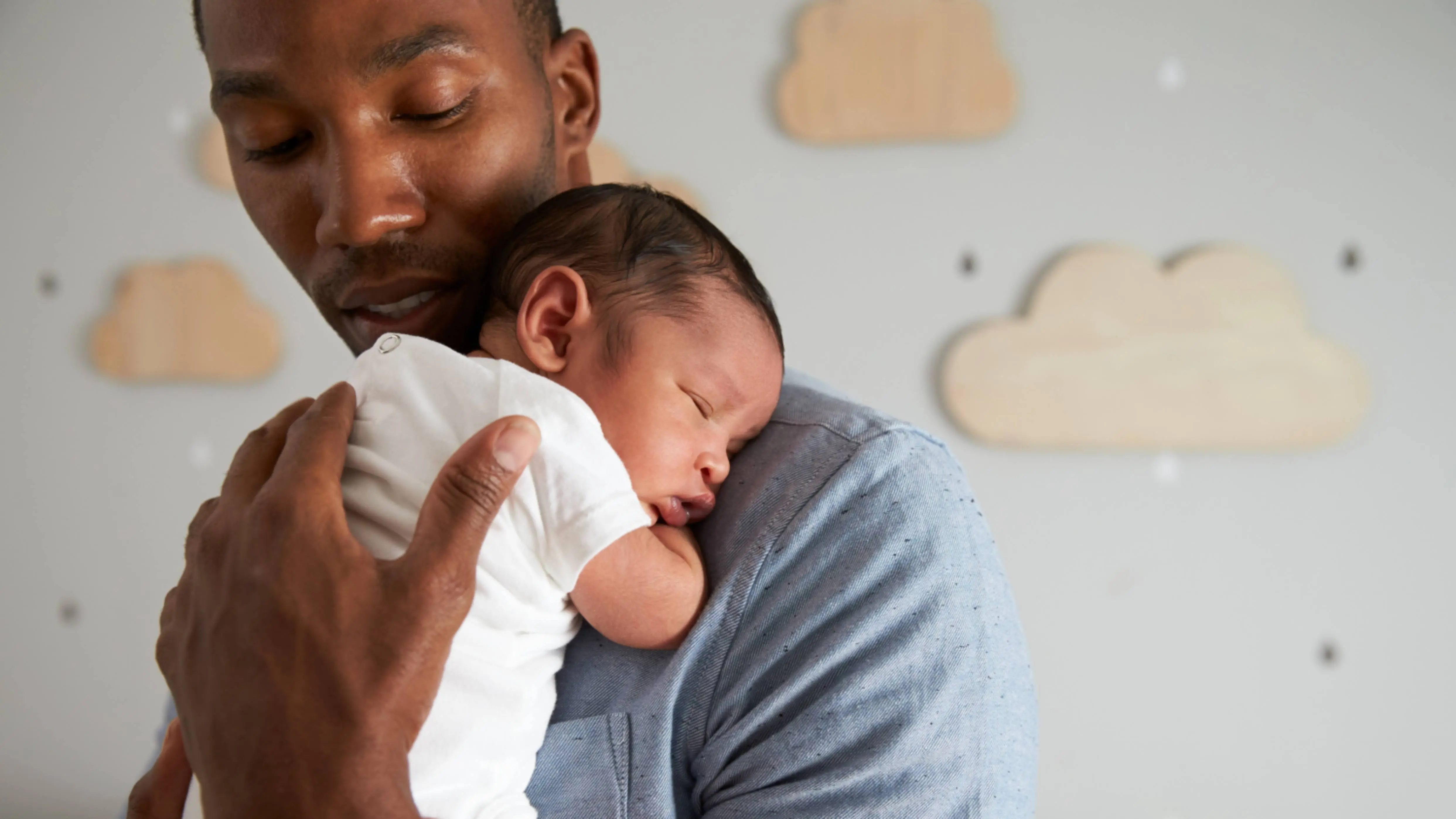 a young adult Black man perhaps a father gently holding an infant new baby 16x9 1